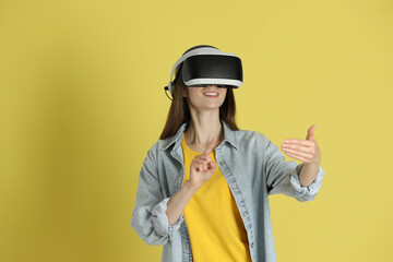 Smiling woman using virtual reality headset on yellow background