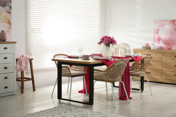 Pink peonies on table with beautiful setting and rattan chairs in dining room