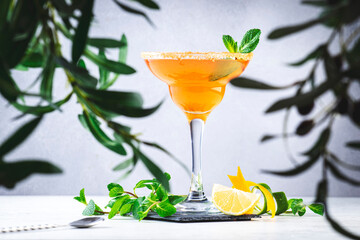 Margarita alcoholic cocktail drink with tequila, syrup, liqueur, lime and lemon juice, mint and ice in glass. Gray background, bar tools