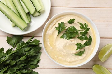Tasty hummus with chickpeas in bowl and fresh products on wooden table, flat lay