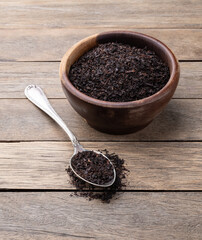 Black tea dried leaves on a bowl over wooden table