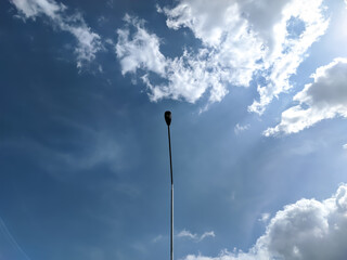 A captivating shot of a streetlamp from below against a backdrop of a blue sky dotted with clouds.