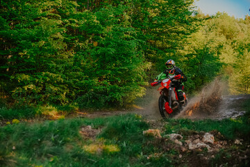 Professional enduro bike rider on action, dirt ride on the muddy road. Motocross sport. 