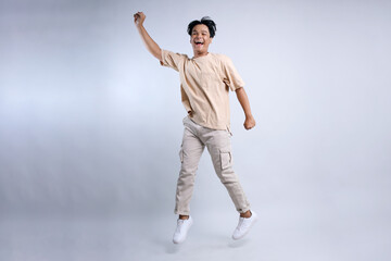 Front View Of Happy Young Asian Stylish Guy Jumping High And Showing Approved Gesture 