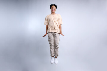 Full Length View Of Young Asian Guy Wearing Casual Clothes Jumping High And Showing Ok Sign With Hands Gesture 