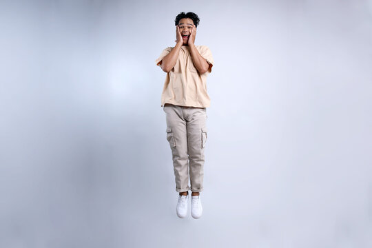 Attractive Young Asian Stylish Man Jumping High And Showing Shocked Gesture 