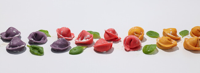 Сolored dumplings and basil on white background
