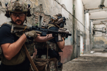Fototapeta premium Soldiers with weapons having mission and hiding in abandoned building.