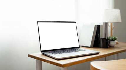 Fototapeta premium Open laptop with blank screen on a wooden desk in a kitchen room home office.