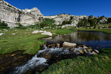 Lee Vining Creek flows through a green meadow beneath North Peak in the Hoover Wilderness of...