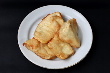 food made from thinly sliced ​​breadfruit coated in a wheat flour mixture then fried until dry and crispy. Fried breadfruit isolated on black background.