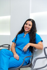 Obraz premium Portrait of latin hispanic woman nurse or dentist sitting using blue dentistry uniform at dental hospital. Medical attention concept.