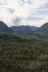 Fototapeta premium Clouds over mountains and green trees on a summer day in the Matanuska-Susitna Valley in Alaska.