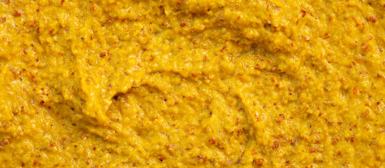 Mustard sauce with grains close-up. Hot spices as a background. Texture of Dijon mustard.