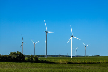 Landscape view of gigantic wind turbines in an agricultural field under clear blue sky, with copy space