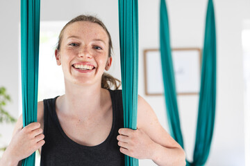 Portrait of happy caucasian teenage girl smiling at aerial yoga class, copy space