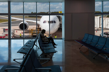 Silhouette of young woman working on laptop and waiting for flight in the Airport - Cancún International Airport  - Cancun, Mexico