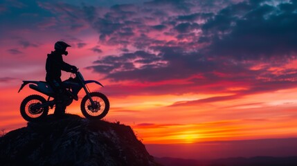 Fototapeta premium Man with dirt bike and beautiful lights Silhouette of a man with a dirt bike on a high rocky peak at a beautiful sunset. Enduro motorcycle travel concept