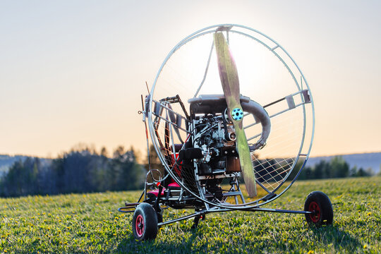 Paragliding machine for paragliding flights on green grass against the bright sun. Preparing paralet with a gasoline engine for flights. Extreme sports