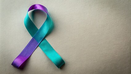 Teal and purple ribbon intertwined, symbolizing suicide prevention awareness, lies on a simple background with ample copy space available.