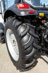 Fototapeta premium Exhibition of agricultural machinery: a close-up of a wheeled tractor with large high-pass tires.