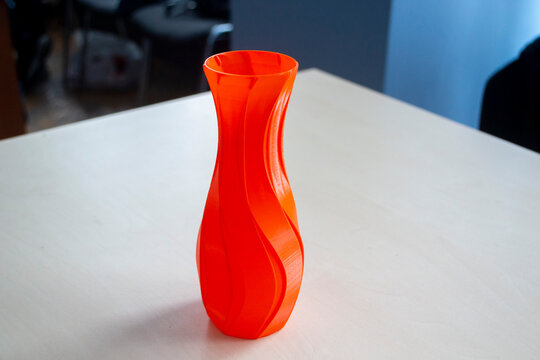 Object in the form of a vase of red color printed on a 3D printer. Three-dimensional model printed on a 3D printer from molten plastic of red color. Concept 3D Printing. FDM 3D Printing technology