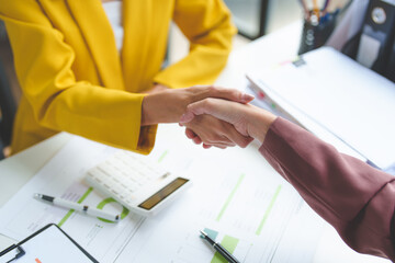 Businesswoman and financial representative shake hands after agreeing on a budget for business expansion and investment. Plans for construction projects Real estate finance concepts.