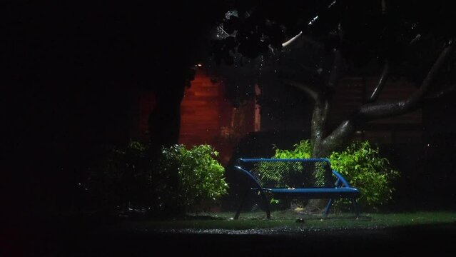 Banca de parque iluminada bajo la lluvia
