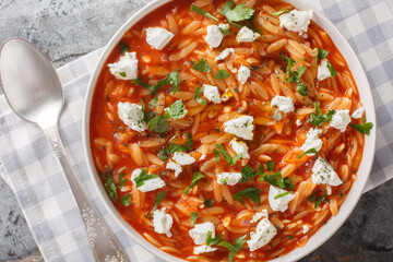 Traditional Greek pasta kritharaki or orzo with spicy tomato sauce, cheese, garlic, onion, carrots closeup on the plate on the table. Horizontal top view from above