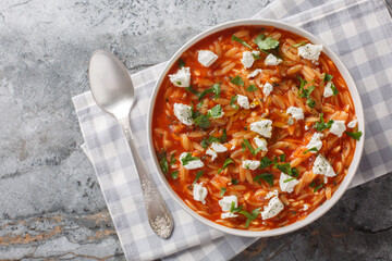 Delicious vegetarian food pasta kritharaki or orzo with spicy tomato sauce, cheese, garlic, onion, carrot closeup on the plate on the table. Horizontal top view from above