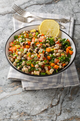 Black-eyed bean salad with carrots, onions, tomatoes, basil, parsley dressed with olive oil closeup on the plate on the table. Vertical