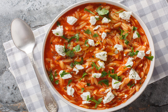 Comfort food pasta kritharaki or orzo with spicy tomato sauce, feta, garlic, onion, carrot closeup on the plate on the table. Horizontal top view from above