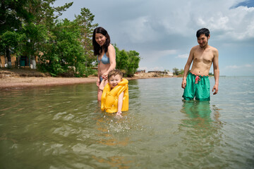 Mom and father have fun in summer with son in yellow life jacket