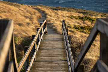 Wooden Coastal steps to the beach through golden coastal grass
