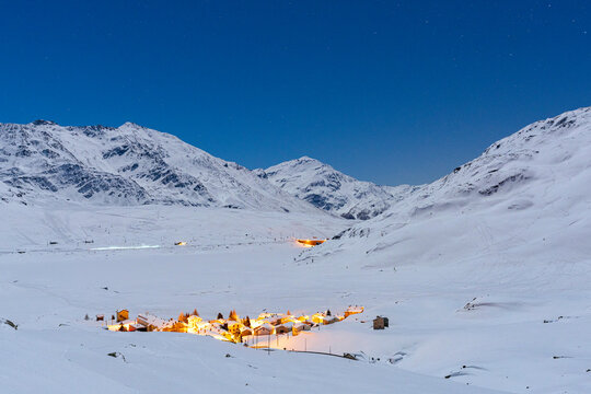 Snowy alpine village of Montespluga lit by moon, Lombardy, Italy