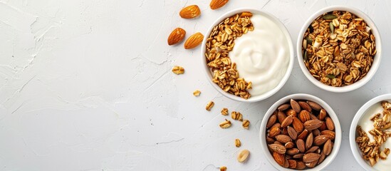 Top view of yogurt, granola, and almonds in bowls on a white surface with copy space image for an organic breakfast recipe concept.