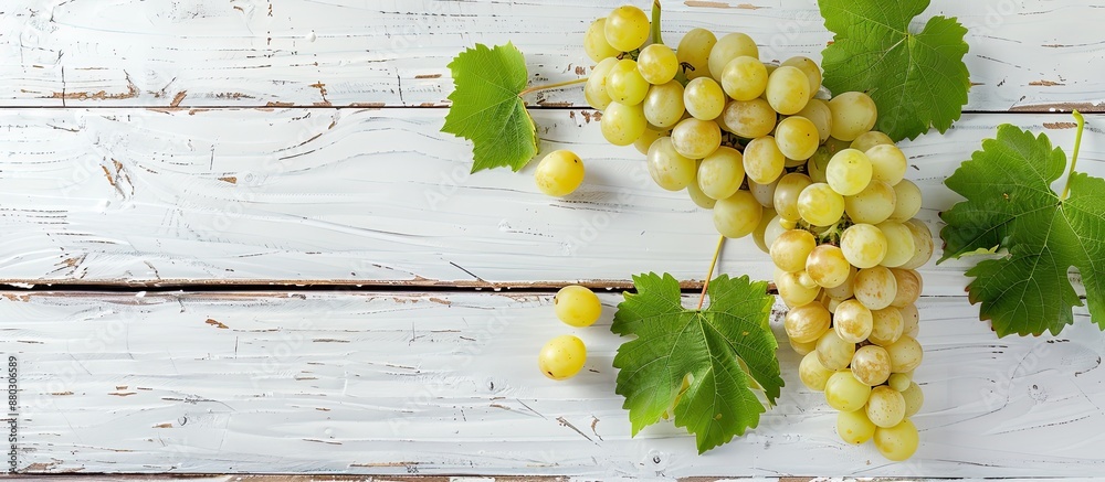 Poster fresh white grapes on a white wooden surface with a top view, providing ample copy space image.