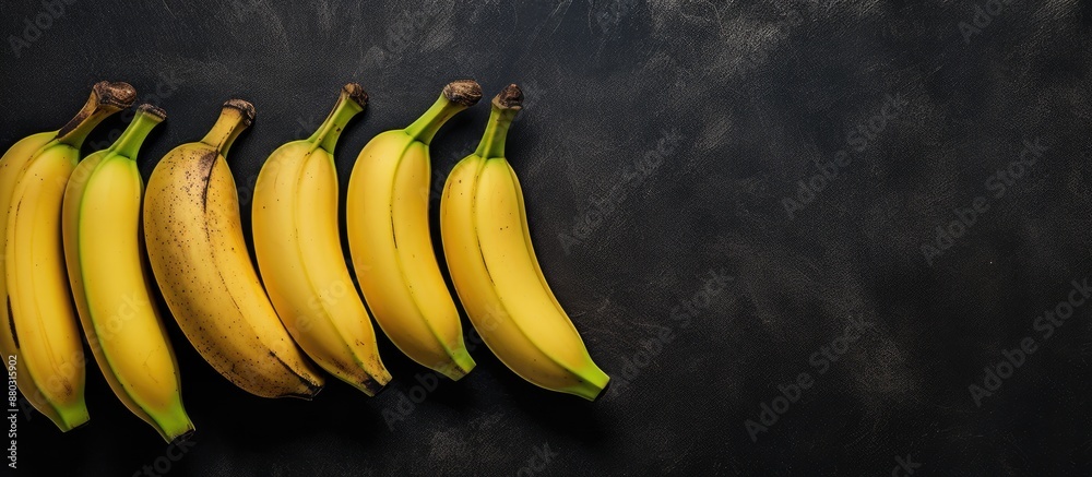 Poster Aerial perspective showing four bananas on a dark slate surface with copy space image to the right.