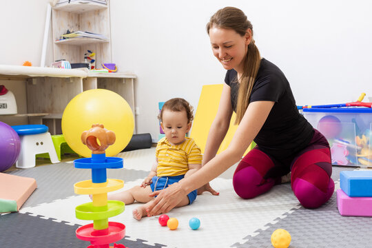 Physiotherapist assisting a young child with neurodevelopmental disorder while physical therapy for motor skills and correcting faulty coordination in rehab center