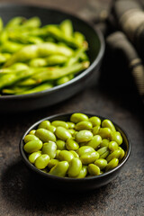 Green edamame pods. Fresh soybeans in bowl on black table.