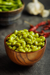 Green edamame pods. Fresh soybeans in bowl on black table.