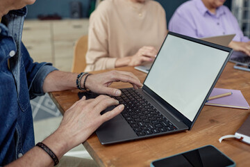 Obraz premium Side view closeup of senior man using laptop with blank white screen in computer class for elderly with focus on hands typing copy space