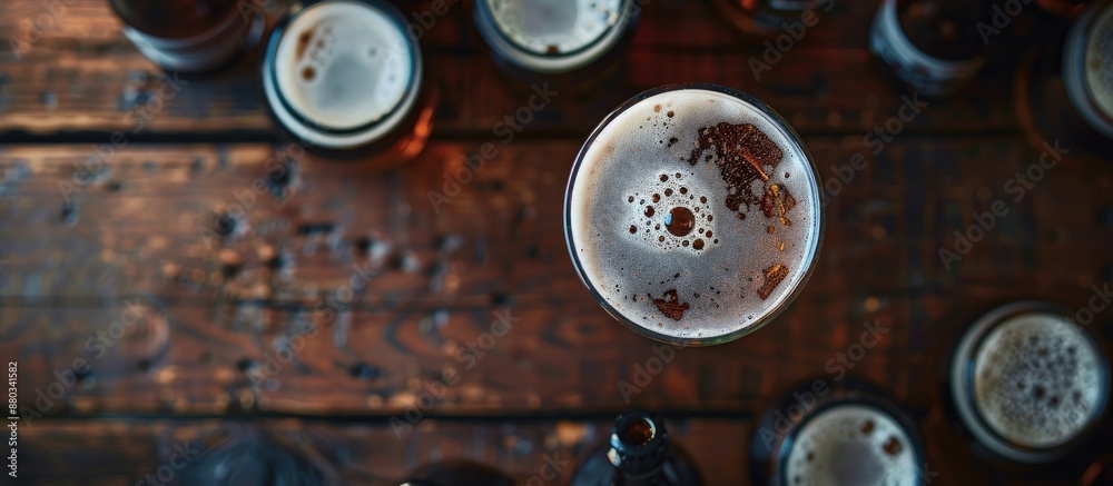 Poster Top view of a beer glass on a wooden table with beer bottles around it The image features selective focus and a blank template for copy space