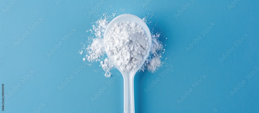 Leinwandbilder white powder in a plastic spoon arranged on a blue background in a composition ideal for adding text