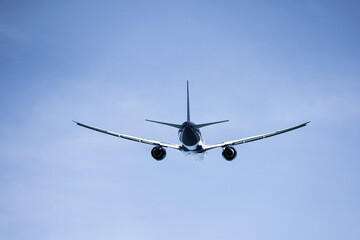 Airplane flying in blue sky, back view. Passenger plane at flight, travel concept