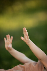 small toddler hands at green nature field on sunset time