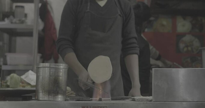 Man cooking street food on a busy street. Chapati is an unleavened flatbread originating from the Indian subcontinent and is a staple in India, Nepal, Bangladesh, Pakistan, Kyrgyzstan, Sri Lanka, the