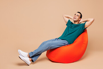 Full body young minded fun middle eastern man wear blue t-shirt casual clothes sit in bag chair...
