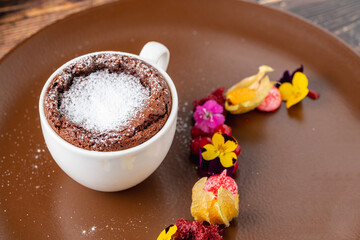 Chocolate souffle with flowing chocolate on a brown porcelain plate