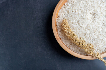 top view a wooden bowl of rice with stalk of rice plant on stone table